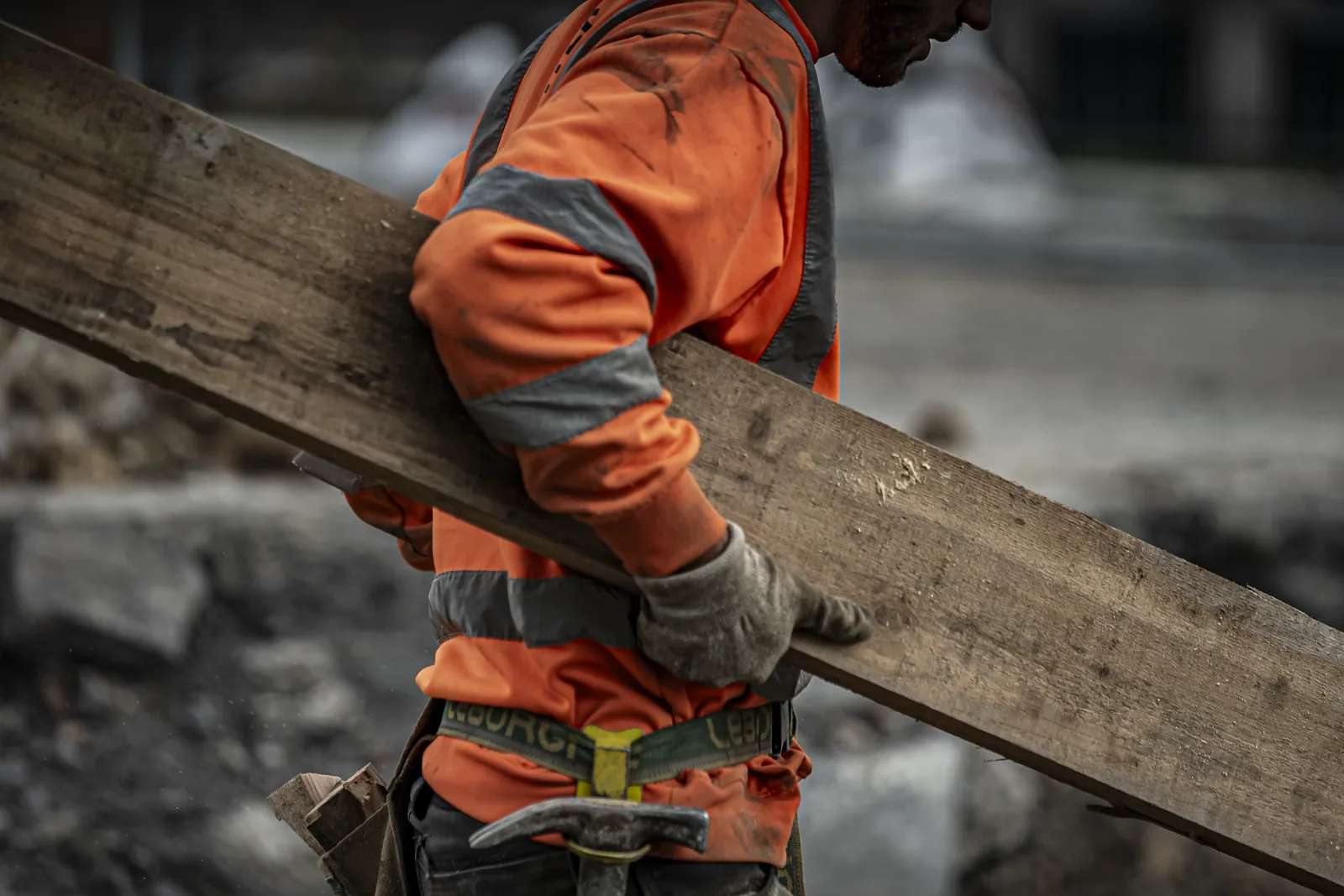 Reportage chantier BTP, ouvrier portant une planche de bois